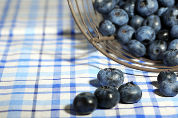 Tasty ripe blueberries in metal basket, on tablecloth