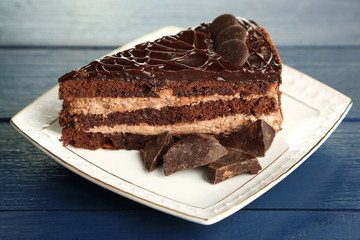 Chocolate cake on plate on color wooden background