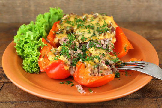 Stuffed red pepper with lettuce on plate on wooden table