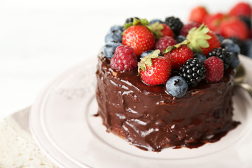 Tasty chocolate cake with different berries, on wooden table