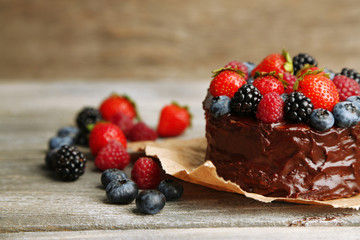 Tasty chocolate cake with different berries on wooden table