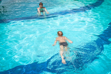 playful father and son having fun in swimming pool