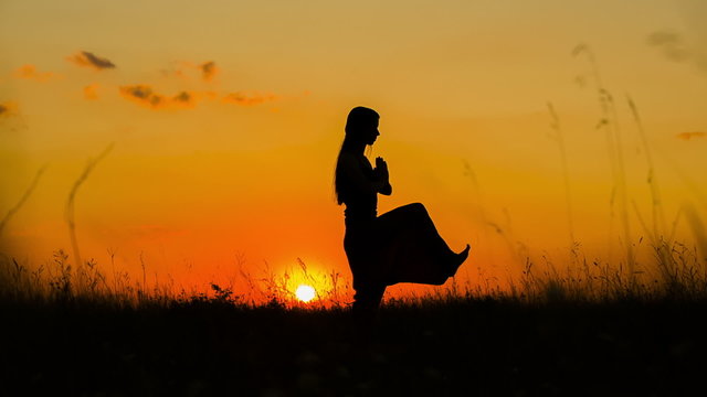 Silhouette of a Young Girl Doing Yoga At Sunset