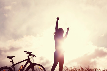 Fototapeta na wymiar Winning girl with bike silhouette