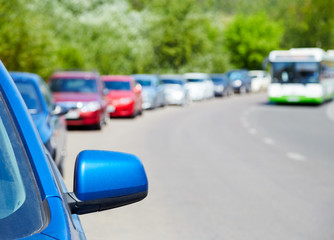 Cars parked on the roadside, bus in the background