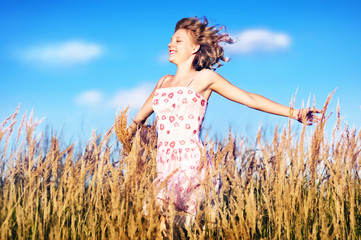 Beautiful young girl running through the high grass