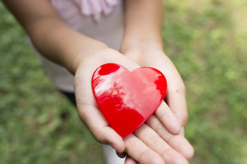 Obraz na płótnie Canvas Hand of a girl holding a toy heart