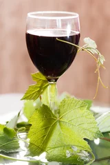 Fotobehang Red wine in glass with grape leaves © Maksim Shebeko