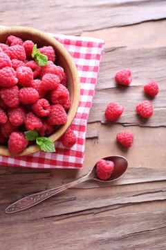 Ripe sweet raspberries in bowl on table close-up