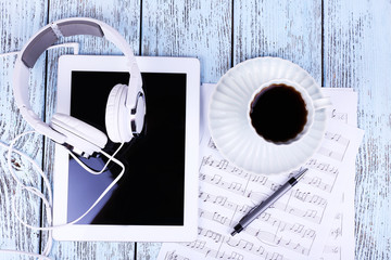 Tablet, cup of coffee printed music and earphones