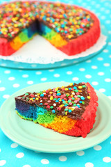 Delicious rainbow cake on plate, on tablecloth background