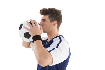 Side view of a football player kissing ball