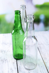 Empty glass bottles on table on bright background
