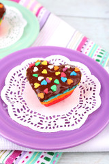 Delicious rainbow cakes on plates, on color wooden background