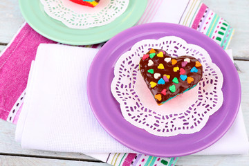 Delicious rainbow cakes on plates, on color wooden background