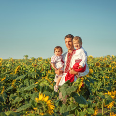 Fototapeta premium A father and two children in Ukrainian costume at sunset in a fi