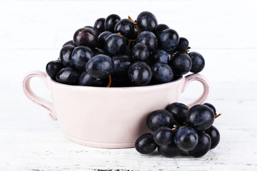 Purple grapes in bowl on wooden background