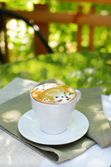 Cup of coffee with cute drawing on table, close up