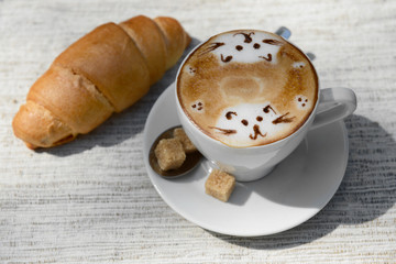 Cup of coffee with cute drawing on table, close up
