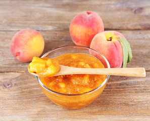 tasty peach jam with fresh peaches on wooden table