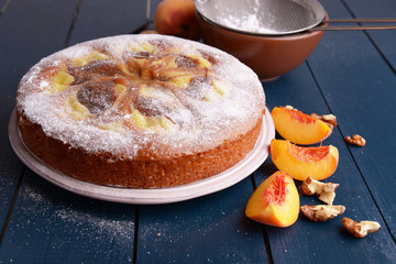 Delicious cake with peach and nuts on wooden table