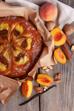 Delicious cake with peach and nuts on wooden table close up