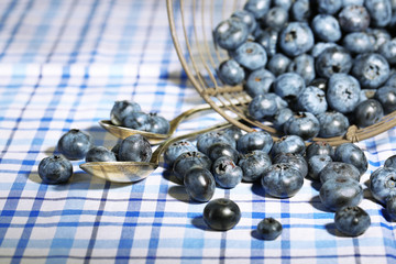 Tasty ripe blueberries in metal basket, on tablecloth