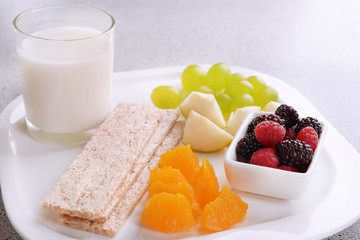 Slices of fruits with crispbreads and glass of milk