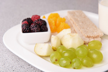Slices of fruits with crispbreads and glass of milk