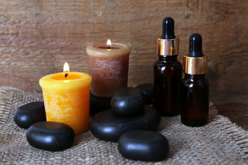 Spa stones, oil and candles on wooden background