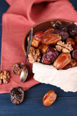 Tasty dates fruits in bowl, on blue wooden background