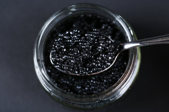 Jar of black caviar and spoon with black caviar