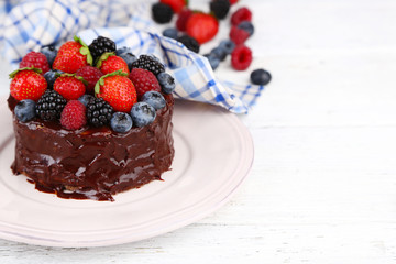 Tasty chocolate cake with different berries, on wooden table