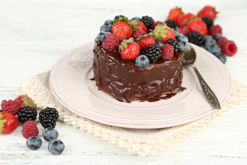 Tasty chocolate cake with different berries, on wooden table
