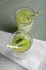 Two glasses of cucumber cocktail on napkin on wooden background