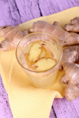 Ginger drink and ginger root on napkin on wooden background