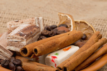 Sweets, cinnamon, nuts and coffee beans on a saucer, on burlap b