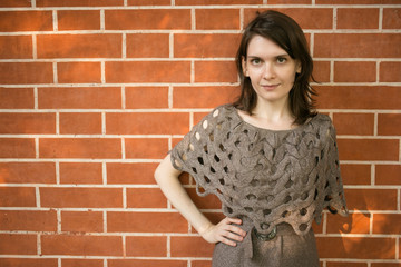 Portrait of woman in knit dress against brick background