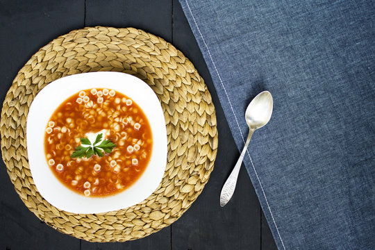 Tomato soup and spoon, top view, dark background