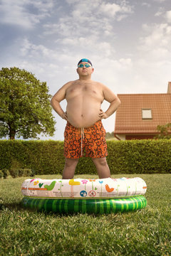 Funny overweight man about to swim in the back yard pool