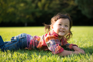 Little adorable girl lying on grass