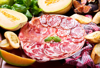plate of various ham and salami with fresh fruits