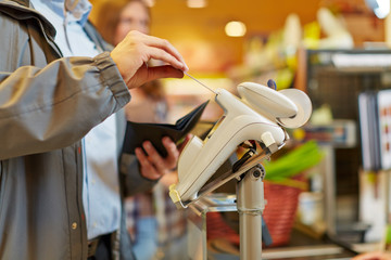 Mann zahlt mit Kreditkarte im Supermarkt