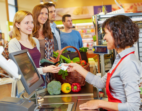 Frau bezahlt mit Geldschein im Supermarkt