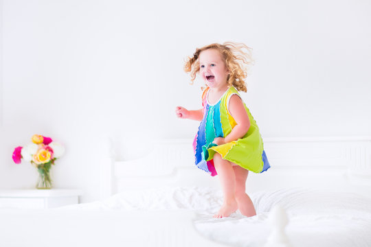 Beautiful little girl jumping on a bed