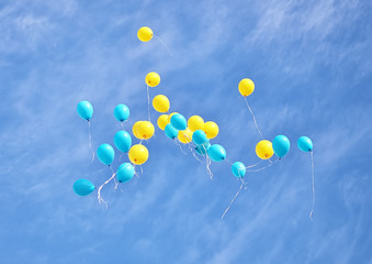 Yellow and blue balloons flying up in the sky