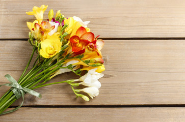 Bouquet of colorful freesia flowers on brown wood