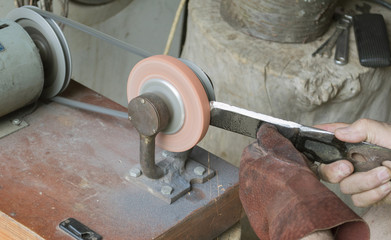 Man sharpening blade for mower