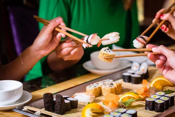 Crédence de cuisine en verre imprimé Bar à sushi Les jeunes mangent des sushis dans un restaurant asiatique