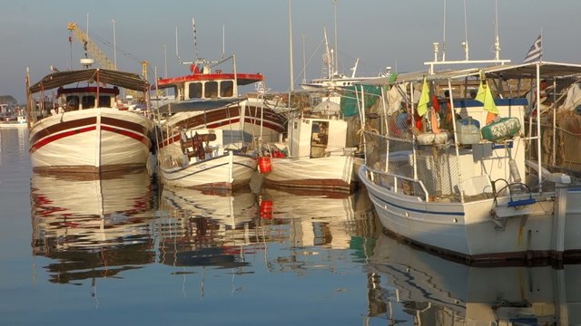 Fishing boats in port with reflections on sea water